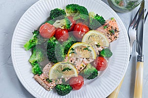 Baked salmon fillet with broccoli and tomato on plate, horizontal, top view