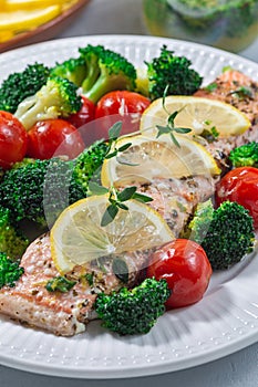 Baked salmon fillet with broccoli and tomato, salmon steak with vegetables, vertical, closeup