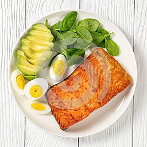 Baked salmon fillet with eggs , spinach, avocado