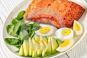 Baked salmon fillet with eggs , spinach, avocado