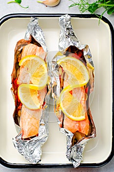 Baked Salmon in Foil, Cooked Fish with Vegetables in a baking dish on Bright Backround, Healthy Eating