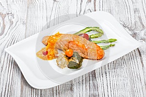 Baked salmon garnished with physalis, asparagus, tomatoes with herbs