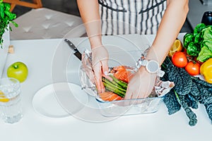 Baked salmon with green asparagus recipe steps. Step two. Woman putting sliced fresh salmon into the foiled baking form