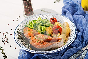 Baked salmon steak with cauliflower, tomatoes and herbs.