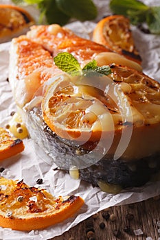 Baked salmon steak with oranges macro on the table. Vertical