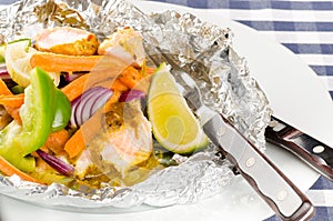 Baked salmon with vegetables in a foil with sause end lime wedge