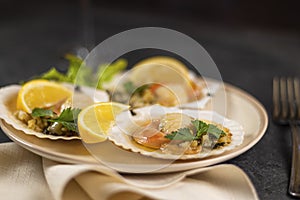 Baked scallops with caviar in a plate against the background. Scallops with lemon on a black background with a napkin