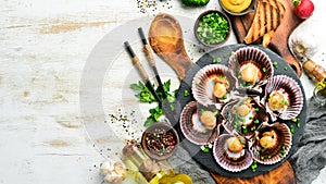 Baked scallops in seashells with garlic and spices on a black stone plate. Seafood. Top view.