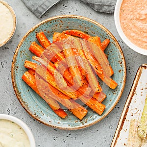 Baked season carrot sticks with sauce and hummus. Vegetarian healthy food