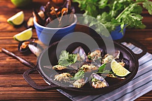 Baked shellfish mussels with cheese, cilantro and lime