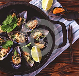 Baked shellfish mussels with cheese, cilantro and lime