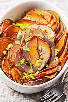 Baked sliced sweet potato with green onions in white dish