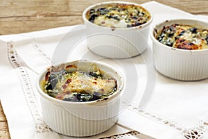 Baked spinach with cheese in small casserole servings, white nap photo