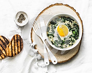 Baked spinach eggs - delicious breakfast, brunch, snack on a light background photo