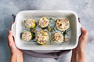 Baked stuffed zucchini columns with minced chicken and vegetables in a ceramic baking dish.