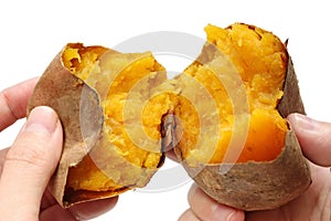 Baked sweet potato divided in half by hands