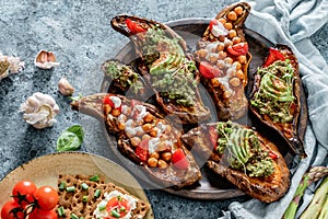 Baked sweet potato toast with roasted chickpeas, tomatoes, goat cheese, sauce guacamole, avocado, seedlings on wooden board