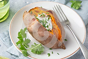 Baked sweet potato with yogurt sausce on white plate