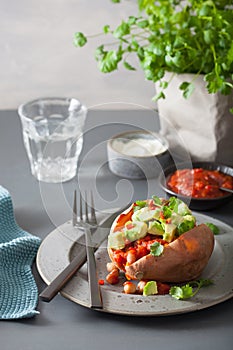 Baked sweet potatoes with avocado chili salsa and beans