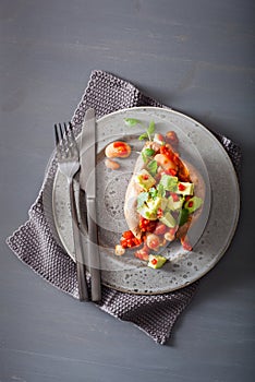 Baked sweet potatoes with avocado chili salsa and beans