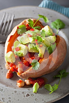 Baked sweet potatoes with avocado chili salsa and beans