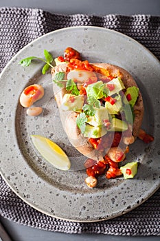 Baked sweet potatoes with avocado chili salsa and beans