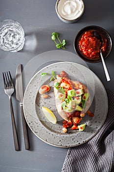 Baked sweet potatoes with avocado chili salsa and beans