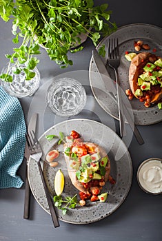 Baked sweet potatoes with avocado chili salsa and beans