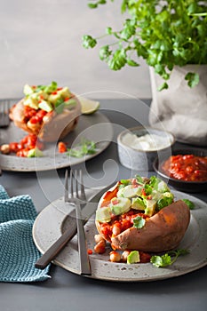 Baked sweet potatoes with avocado chili salsa and beans