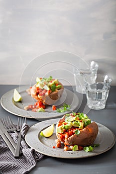 Baked sweet potatoes with avocado chili salsa and beans