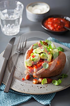 Baked sweet potatoes with avocado chili salsa and beans