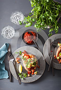 Baked sweet potatoes with avocado chili salsa and beans