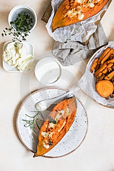 Baked sweet potatoes with mozzarella, herbs and creamy dip on concrete background. Top view
