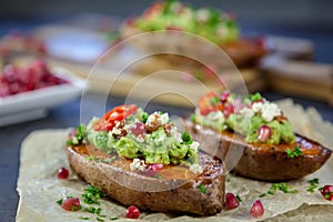 Baked sweet potatoes served with guacamole, feta cheese and pomegranate