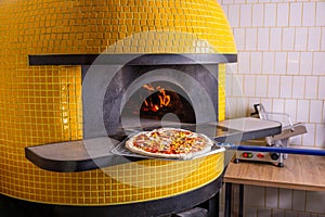 Baked tasty pizza in raditional wood oven in restaurant, Italy. Red hot coal. Italian pizza is cooked in a wood-fired