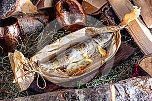 Baked trout with lemon in a basket on a wooden background