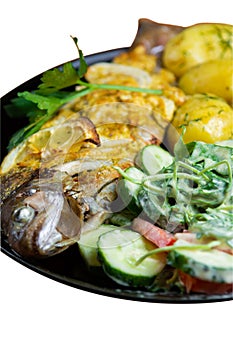 Baked trout on a plate with a salad of arugula, tomatoes, cucumbers and young potatoes with dill isolated on white background