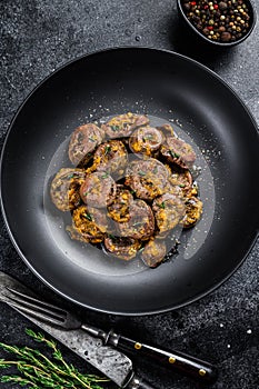 Baked turkey hearts offals with onion. Black background. Top view