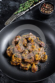 Baked turkey hearts offals with onion. Black background. Top view