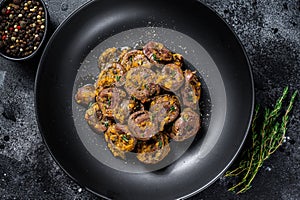 Baked turkey hearts offals with onion. Black background. Top view