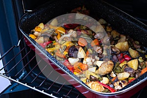 Baked vegetables on a red baking sheet.  Vegetable stew on a baking sheet in the oven