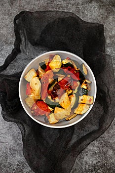 Baked vegetables in the white dish. Baked tomato, zucchini and red pepper.