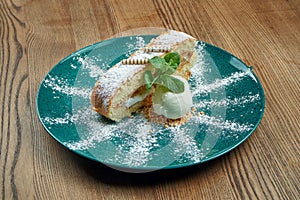 Only baked warm piece of cake with a portion of vanilla ice cream in a blue plate on a wooden background. Tasty pastry dessert.