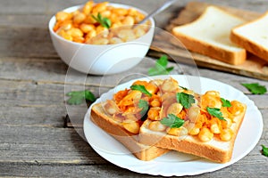 Baked white beans with vegetables on bread and on plate
