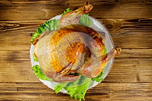 Baked whole chicken on wooden table. Top view