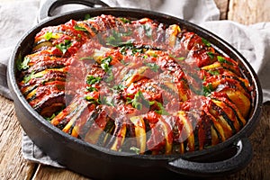 Baked zucchini, potatoes, eggplant and onions in tomato sauce close-up in a pan. horizontal photo