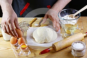 Baker adds eggs to the dough bread, pizza or pie recipe ingredients with hands, food on kitchen table background, working with mil