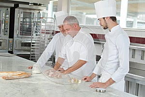 Baker and assistants in bakery kitchen