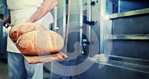 Baker in bakery with bread on shovel