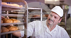 baker in a bakery getting fresh bread out of oven